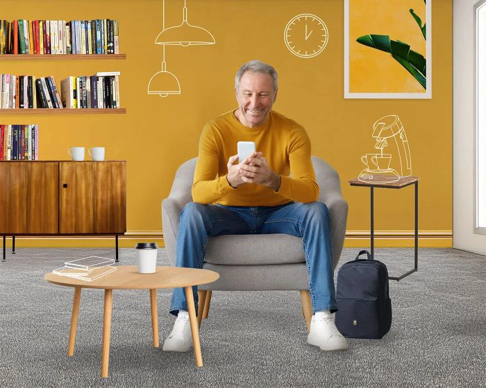 Homme assis confortablement dans un salon cosy, souriant en consultant son
téléphone